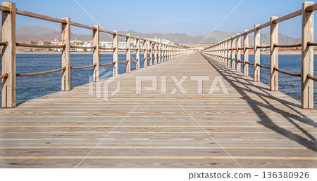 Wooden long pier by the ocean close up. Wooden long pier by the ocean close up. 136380926