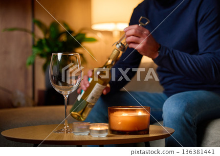 Man opening bottle of white wine with corkscrew at home Man opening bottle of white wine with corkscrew at home 136381441