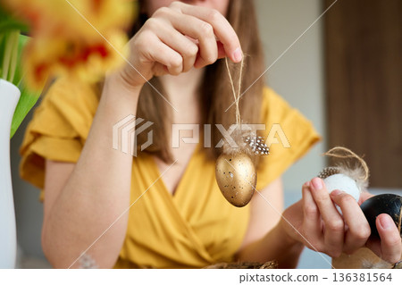 Woman holding handmade Easter eggs with feathers and twine 136381564