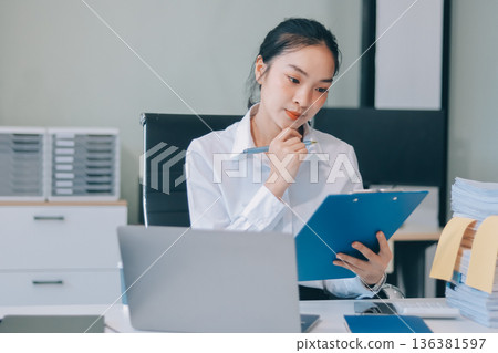 Charming smiling adult woman middle aged woman with curly hair architect designer working on computer in the bright modern office Charming smiling adult woman middle aged woman with curly hair architect designer working on computer in the bright modern office 136381597