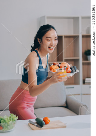 Fit young Asian women in activewear sitting on yoga mat and eating fresh vegetable salad after workout, representing clean eating, fitness lifestyle, wellness routine and health balance. Fit young Asian women in activewear sitting on yoga mat and eating fresh vegetable salad after workout, representing clean eating, fitness lifestyle, wellness routine and health balance. 136381665