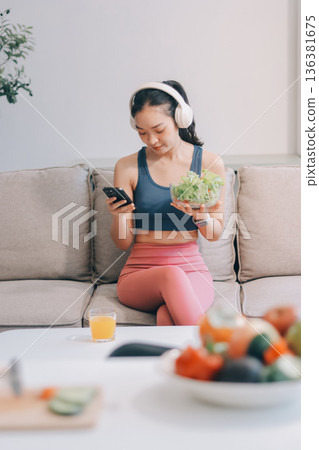 Fit young Asian women in activewear sitting on yoga mat and eating fresh vegetable salad after workout, representing clean eating, fitness lifestyle, wellness routine and health balance. Fit young Asian women in activewear sitting on yoga mat and eating fresh vegetable salad after workout, representing clean eating, fitness lifestyle, wellness routine and health balance. 136381675