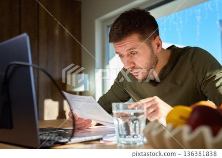 Man checking bills and financial documents at home desk Man checking bills and financial documents at home desk 136381838