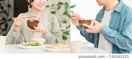 一對年輕的亞洲夫婦在家中餐桌上用餐。 一對年輕的亞洲夫婦在家中餐桌上用餐。 136382335