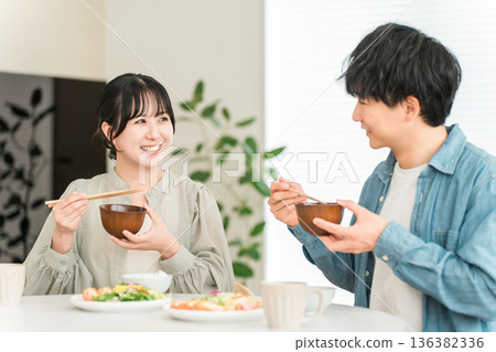 Young Asian couple eating at the dining table in their home Young Asian couple eating at the dining table in their home 136382336