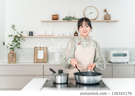Young Asian woman in an apron cooking in the kitchen 136383176