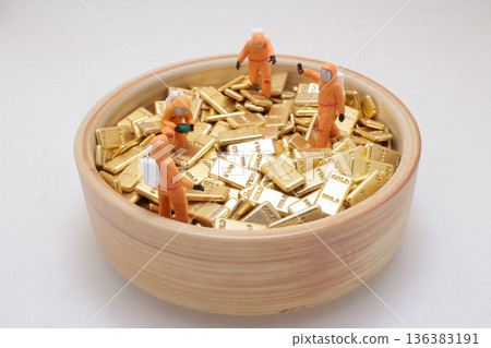 Miniature hazmat workers inspect bowl filled with gold Miniature hazmat workers inspect bowl filled with gold 136383191