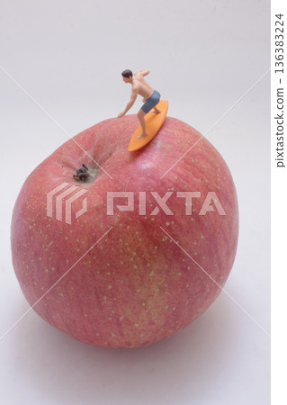 Miniature surfer rides imaginary wave atop giant apple Miniature surfer rides imaginary wave atop giant apple 136383224