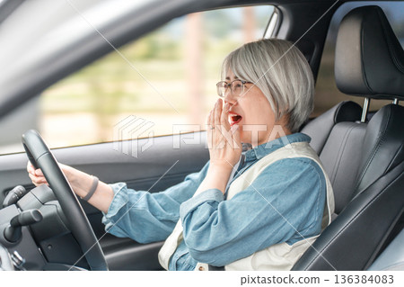 Surprised female elderly driver being surprised while driving Surprised female elderly driver being surprised while driving 136384083