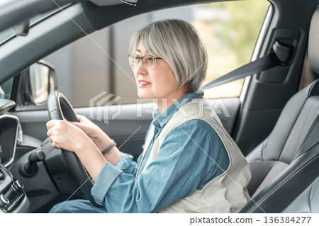Smiling elderly driver woman driving a car Smiling elderly driver woman driving a car 136384277