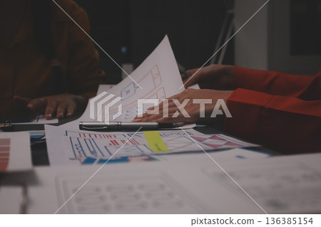 Team of uxui designers pointing at computer screen, discussing new mobile app design in the office Team of uxui designers pointing at computer screen, discussing new mobile app design in the office 136385154