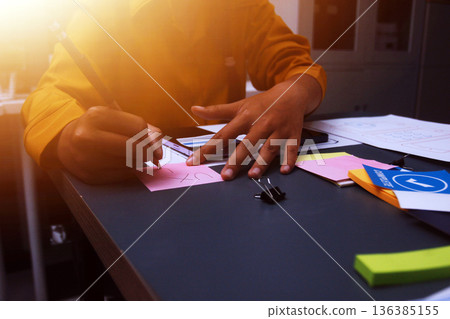 Team of uxui designers pointing at computer screen, discussing new mobile app design in the office Team of uxui designers pointing at computer screen, discussing new mobile app design in the office 136385155
