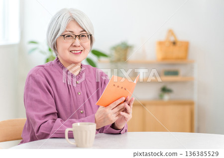 A gray-haired senior woman holding a pension book 136385529