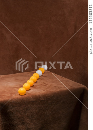 A row of white and yellow balls on a table 136385811