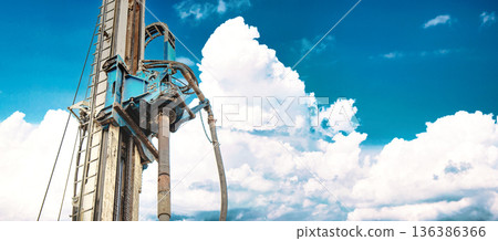 Heavy drilling rig stands tall against a backdrop of clouds while working to extract oil and gas resources during daytime at a drilling site Heavy drilling rig stands tall against a backdrop of clouds while working to extract oil and gas resources during daytime at a drilling site 136386366