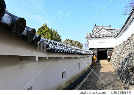 Japanese castle architecture: The path to the castle with tiles bearing family crests and white walls Japanese castle architecture: The path to the castle with tiles bearing family crests and white walls 136386579