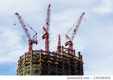 Low-angle view of cranes and steel structures of building construction with a blue sky background in Taipei, Taiwan. 136386838