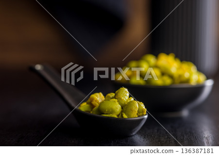Fresh salad with edamame beans on ceramic spoon on black table. 136387181
