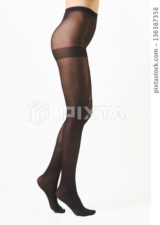 Slender female legs in butt lifting tights standing on tiptoes in profile Slender female legs in butt lifting tights standing on tiptoes in profile 136387358