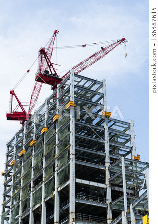 Low-angle view of cranes and steel structures of building construction with a blue sky background in Kaohsiung, Taiwan. Low-angle view of cranes and steel structures of building construction with a blue sky background in Kaohsiung, Taiwan. 136387615
