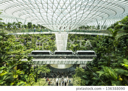 The Skytrain passes through the Rain Vortex at Jewel Changi Airport, Singapore. The world's largest and tallest indoor artificial waterfall, surrounded by a terraced forest. The Skytrain passes through the Rain Vortex at Jewel Changi Airport, Singapore. The world's largest and tallest indoor artificial waterfall, surrounded by a terraced forest. 136388090