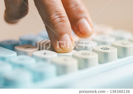 Close-up of a hand pressing calculator keys for budgeting, accounting and financial analysis. Business expense planning, tax calculation, office desk background, copy space for paperwork. 136388136