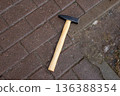 Hammer with wooden handle lying on wet brown paving stones. Hand tool for construction and repair work concept. Top view 136388354
