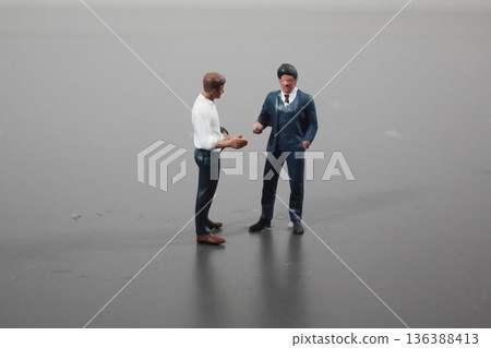 Miniature Figures Engage In Conversation On Neutral Surface 136388413