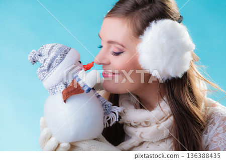 Woman in warm clothes holding snowman toy. Woman in warm clothes holding snowman toy. 136388435