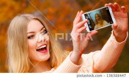 girl taking self picture with phone outdoors 136388447