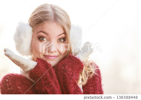Portrait of pretty smiling woman in white earmuffs. 136388448