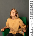 Woman photographer, mother of two children, businesswoman sitting in a green armchair. Concept of successful female entrepreneur lifestyle and business. IT specialist, cafe owner, businesswoman 136388621