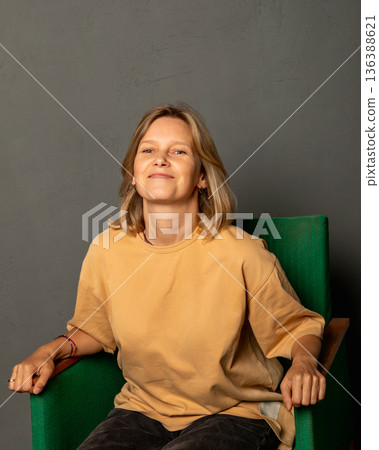 Woman photographer, mother of two children, businesswoman sitting in a green armchair. Concept of successful female entrepreneur lifestyle and business. IT specialist, cafe owner, businesswoman 136388621