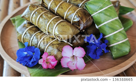Sticky rice stir-fried with coconut milk, wrapped in banana leaves, with a banana filling. Sticky rice stir-fried with coconut milk, wrapped in banana leaves, with a banana filling. 136388665