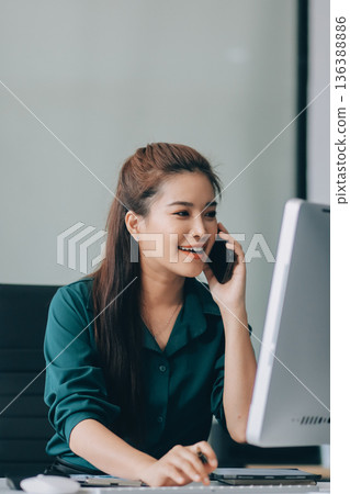 Determined asian businesswoman works late in a modern office, confidently analyzing data on her laptop, embodying success and professionalism with a smile Determined asian businesswoman works late in a modern office, confidently analyzing data on her laptop, embodying success and professionalism with a smile 136388886