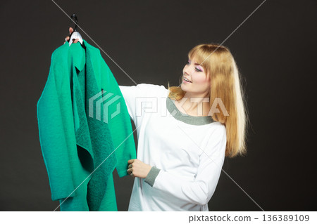 Fashionable woman holding green coat 136389109