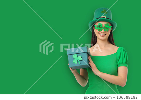 A young woman dressed in green holds a gift box and smiles A young woman dressed in green holds a gift box and smiles 136389182
