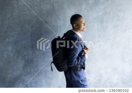 A man in a suit carrying a backpack 136390102