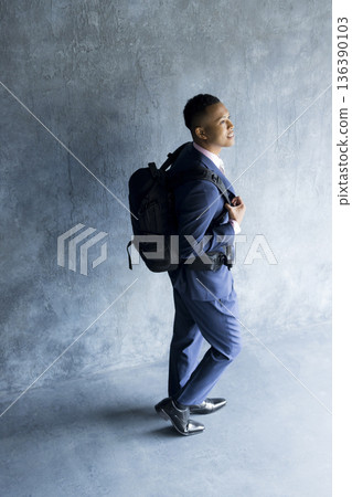 A man in a suit carrying a backpack 136390103