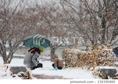 一位家長和孩子在雪地公園的一角製作達摩不倒翁。 一位家長和孩子在雪地公園的一角製作達摩不倒翁。 136390860