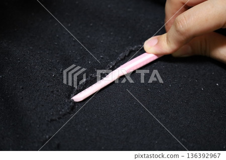 Close-up of hands removing lint from clothes. Scene of using a razor to care for clothes. 136392967