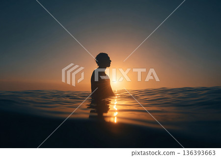 The tranquil reflection of a freediver on perfectly still ocean water at sunrise, creating a mirror-like image of profound peace. 136393663