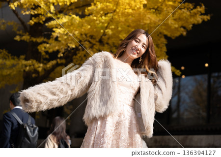 A woman walking through a park with autumn leaves A woman walking through a park with autumn leaves 136394127