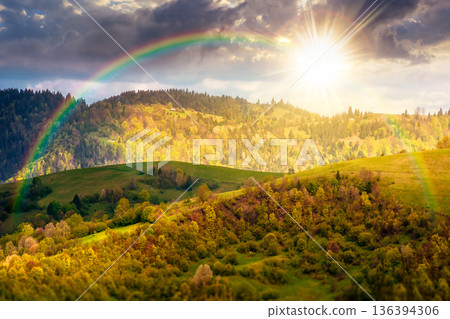 rural area in mountain landscape at sunset. deciduous forest on a steep green hill. alpine countryside scenery during spring in evening dappled light. remote highland under the rainbow rural area in mountain landscape at sunset. deciduous forest on a steep green hill. alpine countryside scenery during spring in evening dappled light. remote highland under the rainbow 136394306