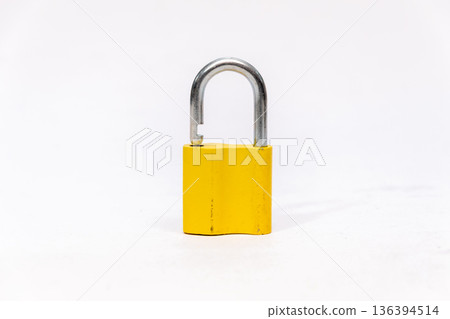 Yellow metal padlock stands on a light isolated background. 136394514