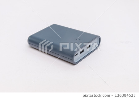 Gray external battery lies on a light isolated background. Gray external battery lies on a light isolated background. 136394525