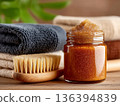 Natural body scrub jar with brush and towels arranged in a spa wellness concept. Organic skincare and clean beauty lifestyle. Perfect for cosmetic branding, spa marketing and wellness concepts. 136394839
