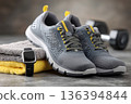 High-quality fitness footwear with smartwatch, towel , and workout gear arranged in a clean modern gym. Running shoes and dumbbell. Training accessories, active lifestyle, motivation, exercise habits. 136394844