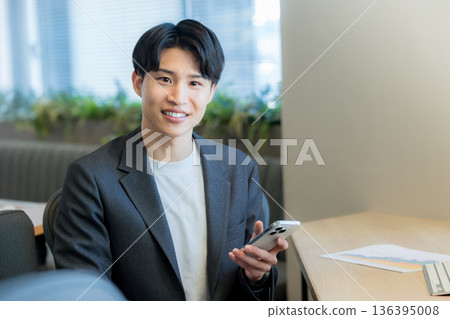 一個在辦公室使用智能手機的商人 一個在辦公室使用智能手機的商人 136395008