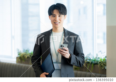 A businessman who uses a smartphone in the office A businessman who uses a smartphone in the office 136395010